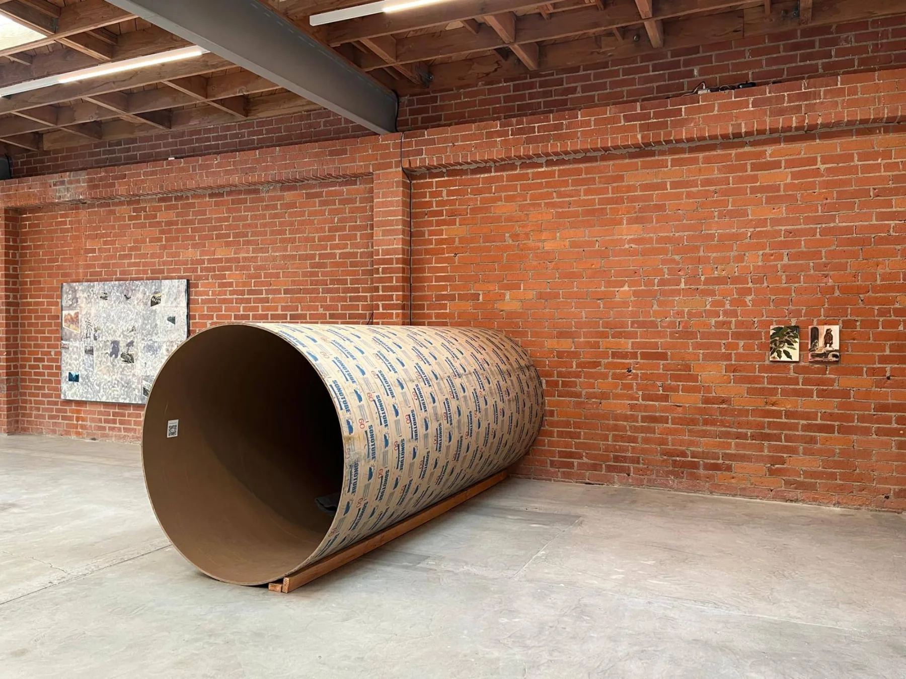 Close view of the sonotube installation against a brick wall at The Brick.