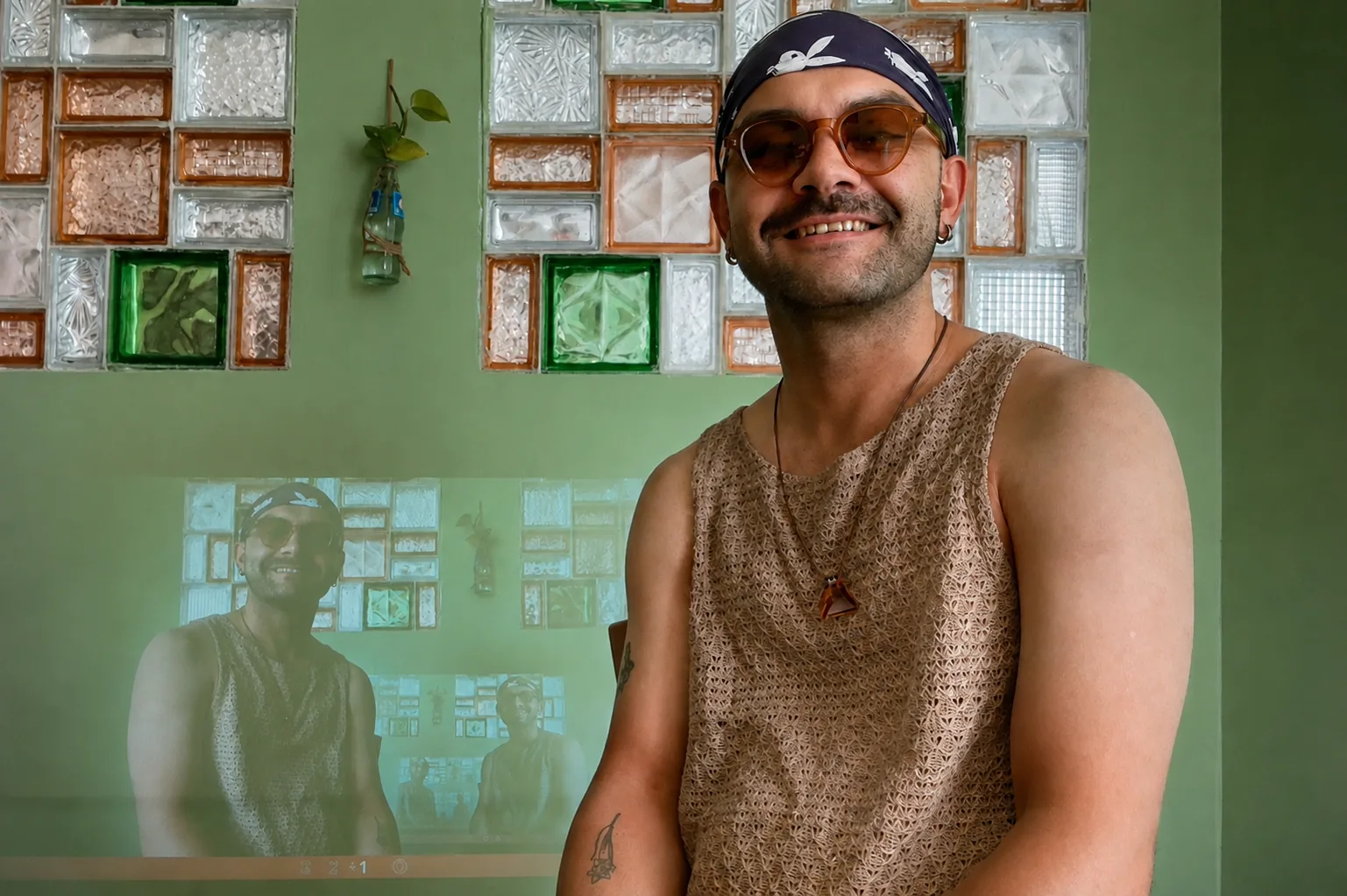 Hodjat Salimi seated in a room with a projected image behind him.